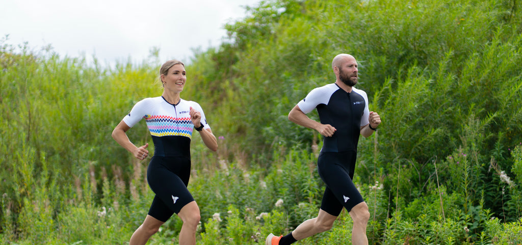 Man and woman standing on the seafront in EVO tri suits